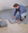 Contractors installing basement subfloor tiles and matting on a concrete basement floor in Springfield, Virginia