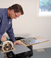 installing a waterproof vapor barrier on a basement floor to prepare for basement carpeting in a Alexandria home
